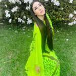 Nãwã Ēma, com vestido e acessório de flor Shavorã.  Vestido verde pintado à mã…